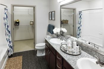 A bathroom with a toilet, sink, and mirror at Regatta Sloans Lake Apartments, Denver